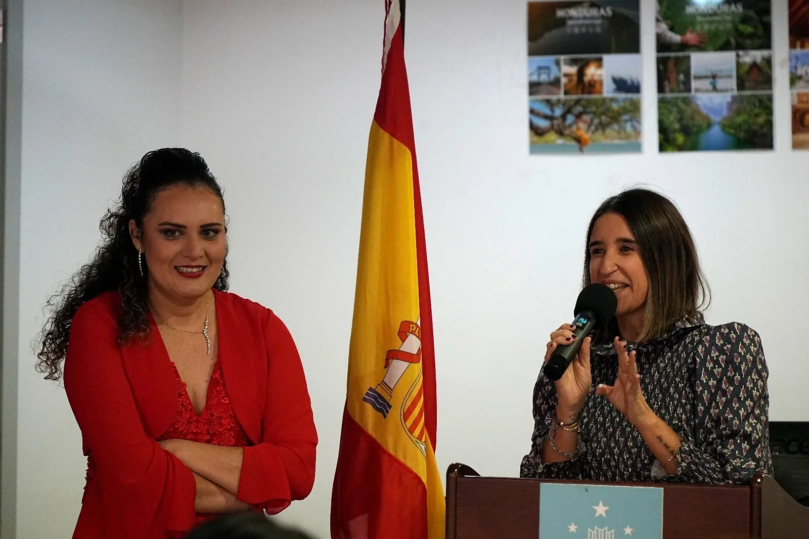 Yadi Villanueva escuchando a una ponente en el atril durante la presentación en el Consulado de Honduras