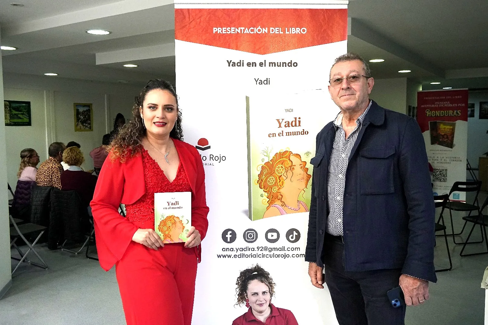 Yadi Villanueva con un invitado junto al cartel de la presentación de Yadi en el mundo en el Consulado de Honduras