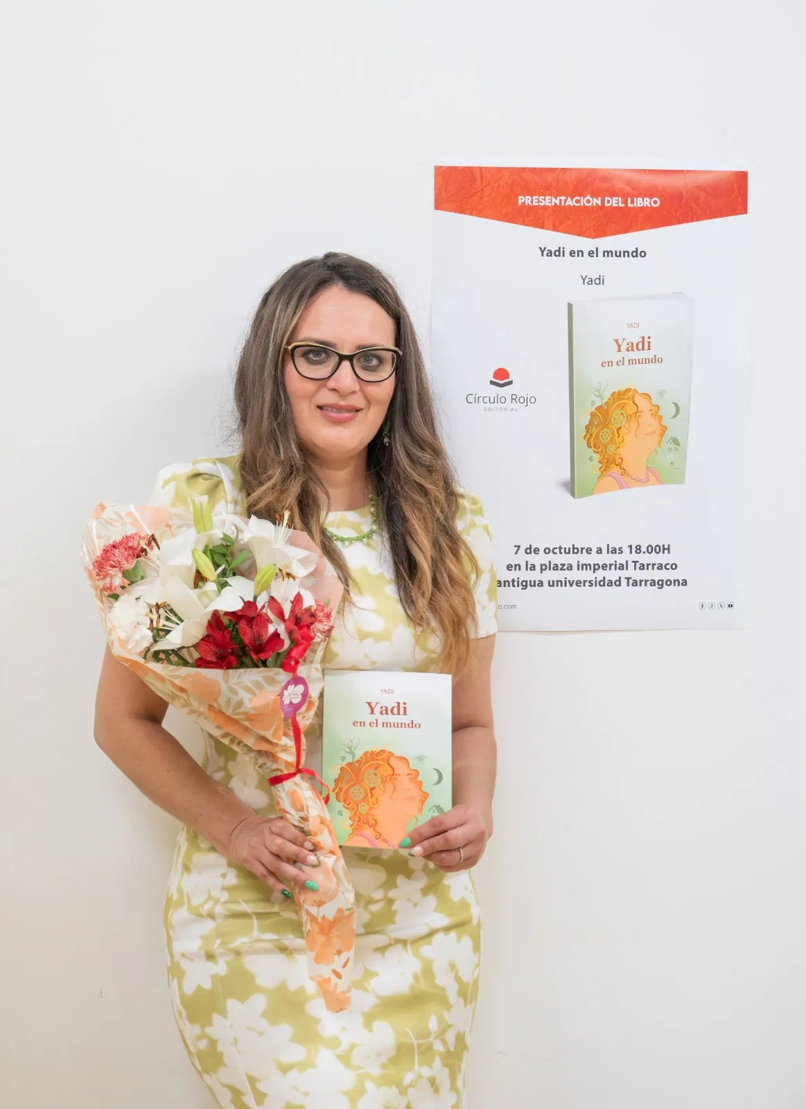 Yadi Villanueva con su libro y un ramo de flores frente al cartel de la presentación