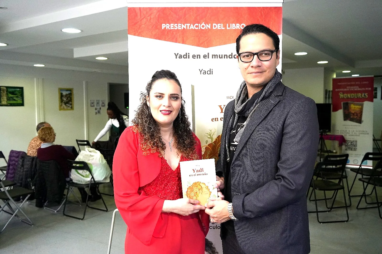 Yadi Villanueva entregando un ejemplar de su libro a un asistente en el Consulado de Honduras